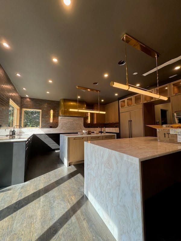 Modern kitchen with island, gray cabinetry, pendant lights, and dark countertops under recessed lighting