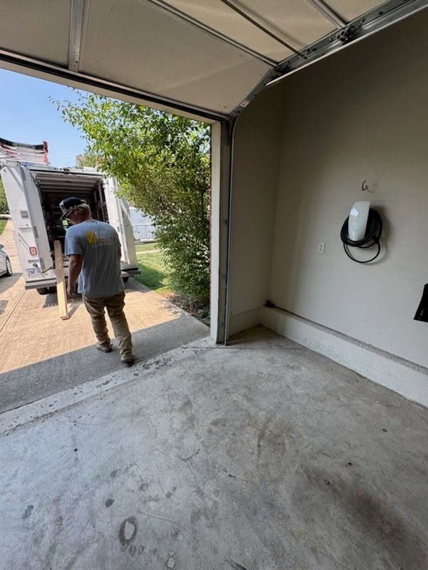 Worker carrying items from a garage into a moving truck outside.