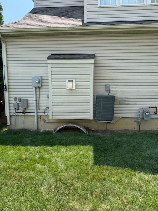 Backyard house exterior with utility meters, HVAC unit, and grassy lawn
