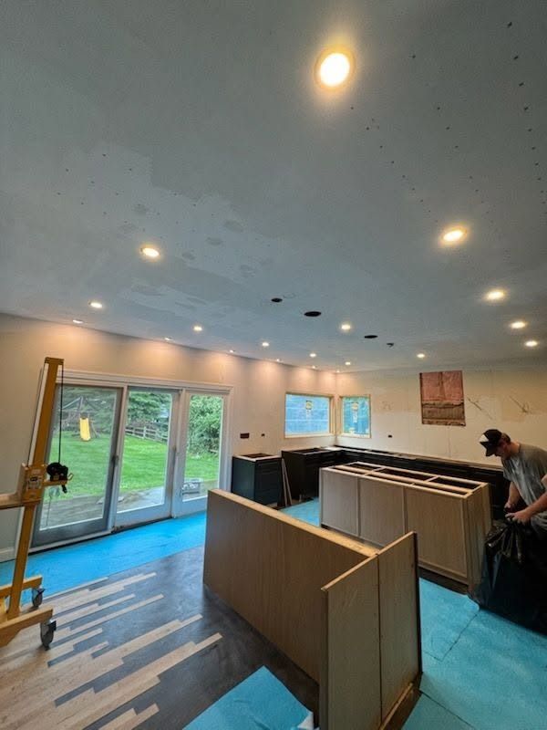 Bright modern kitchen with blue floor, white ceiling lights, and a person working near the counter
