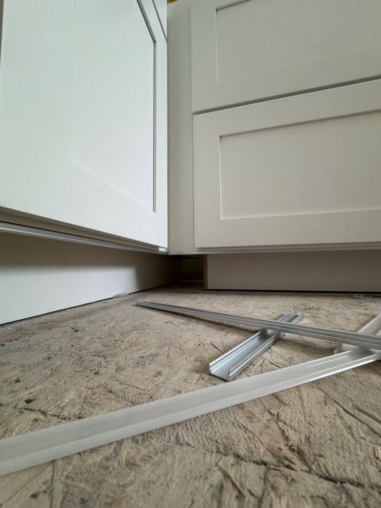 Broken cabinet door and debris on a carpeted kitchen floor