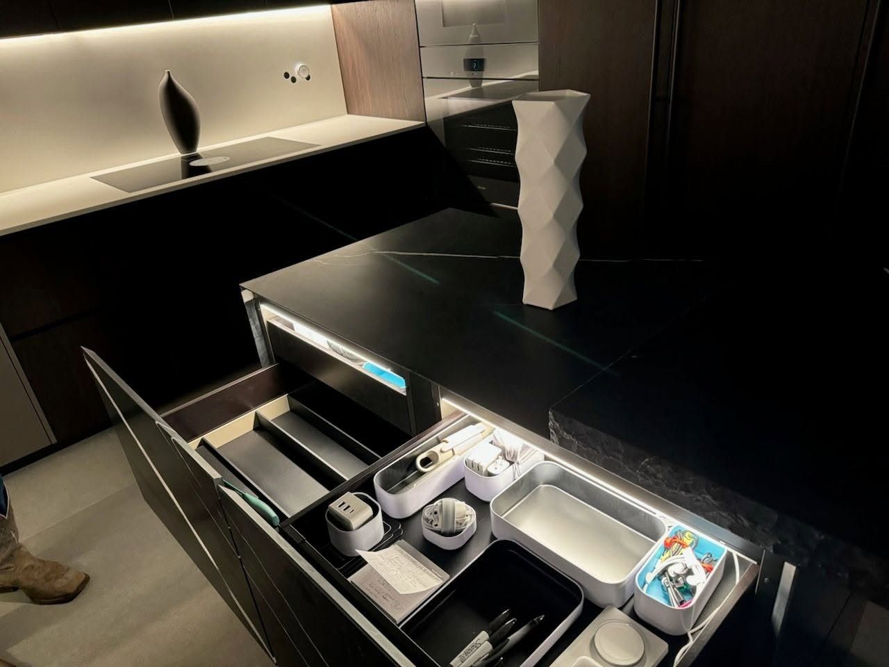 Modern kitchen with black countertops and a slide-out drawer organizer holding cups, utensils, and supplies
