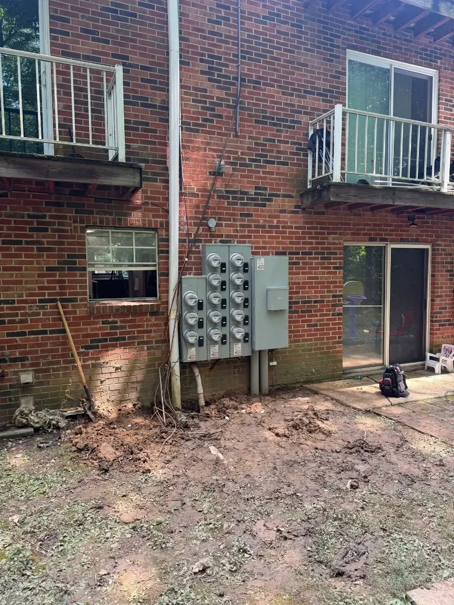 Brick apartment building exterior with balconies, utility meters, and a muddy courtyard.