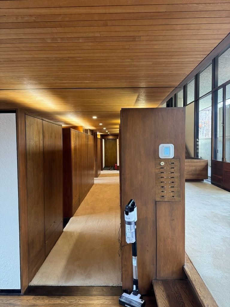 Modern wooden hallway with skylight, glass windows, and a hand sanitizer dispenser by a pillar