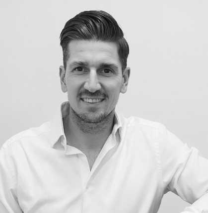 Portrait en noir et blanc d'un homme souriant en chemise blanche sur fond uni