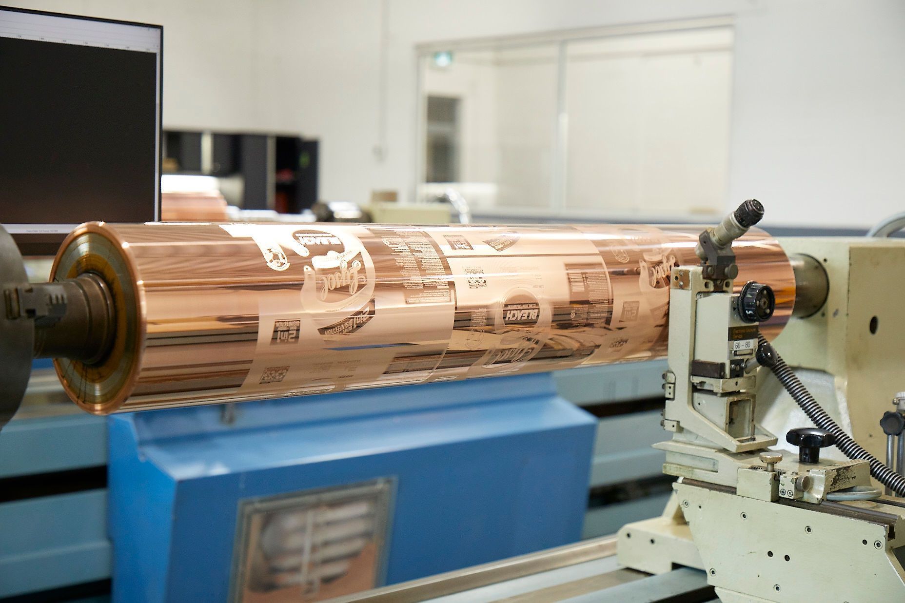 A large copper roller is sitting on top of a lathe in a factory.