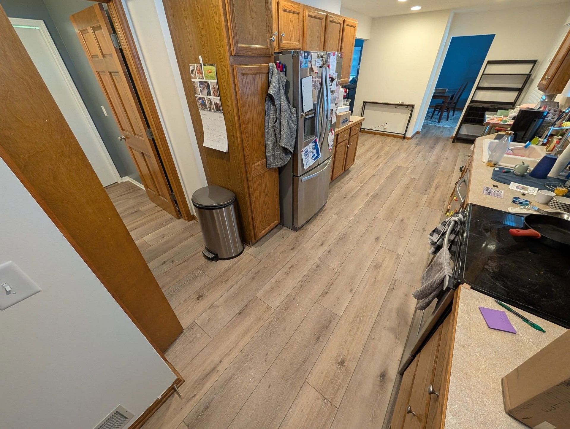 A kitchen with hardwood floors , stainless steel appliances and wooden cabinets.