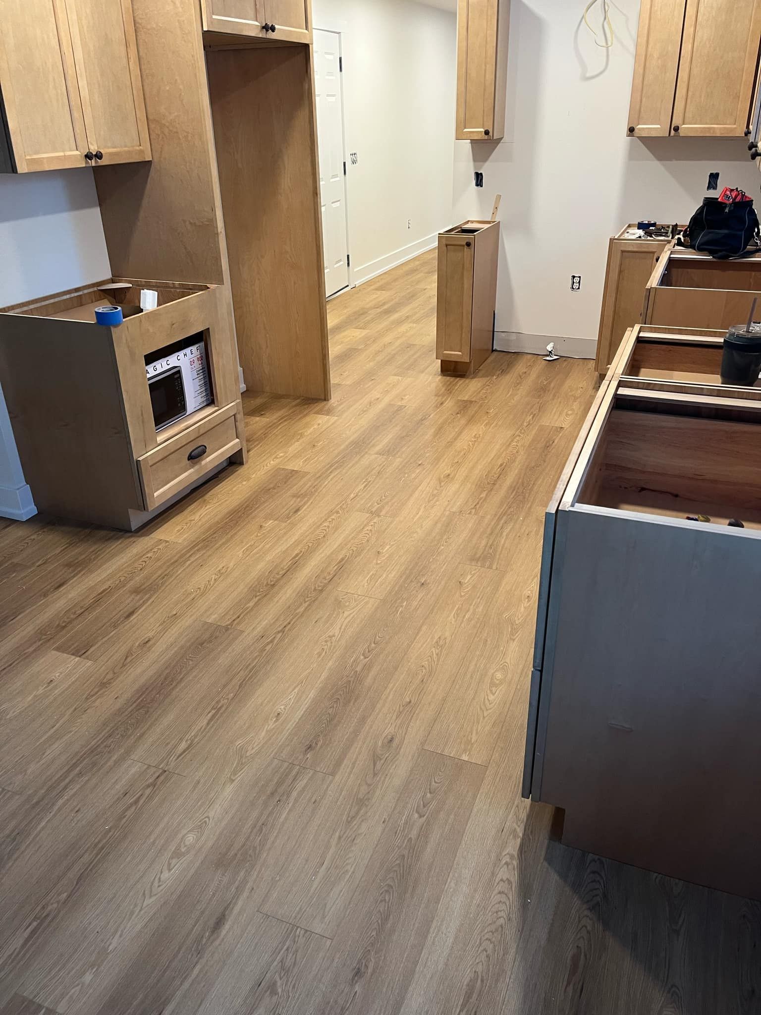 A kitchen under construction with wooden floors and cabinets.