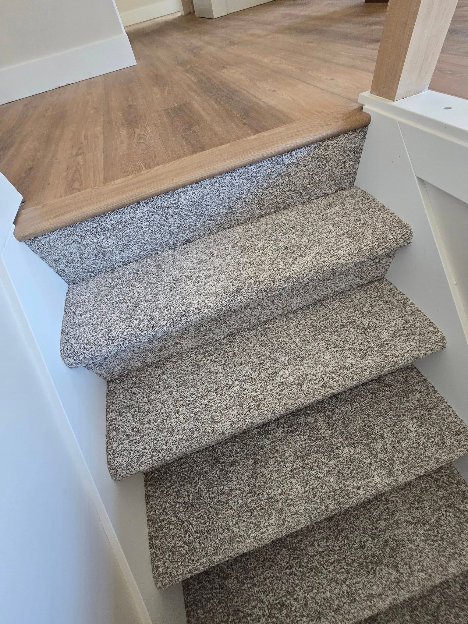 A staircase with a carpeted staircase and a wooden floor.