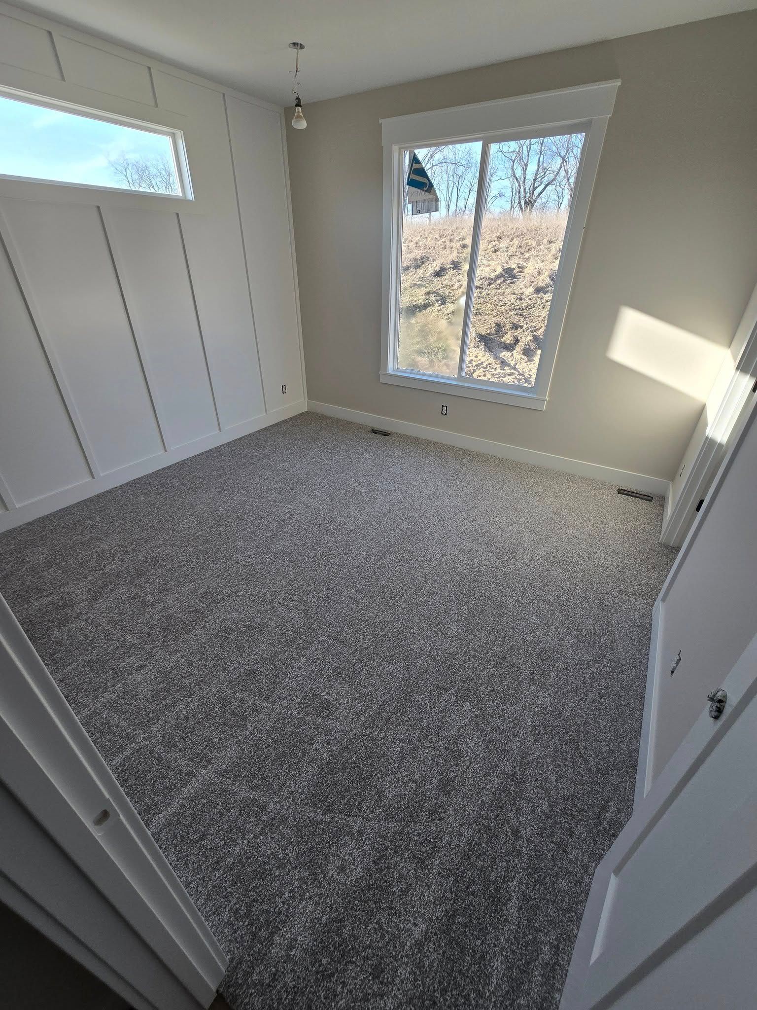 An empty room with a carpeted floor and a window.