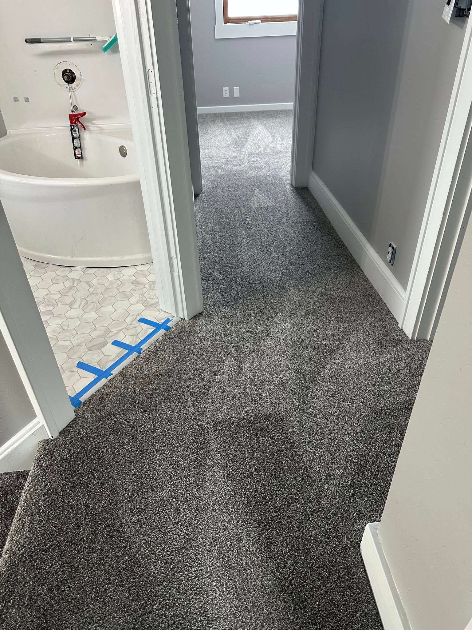 A bathroom with a bathtub and a gray carpeted floor.