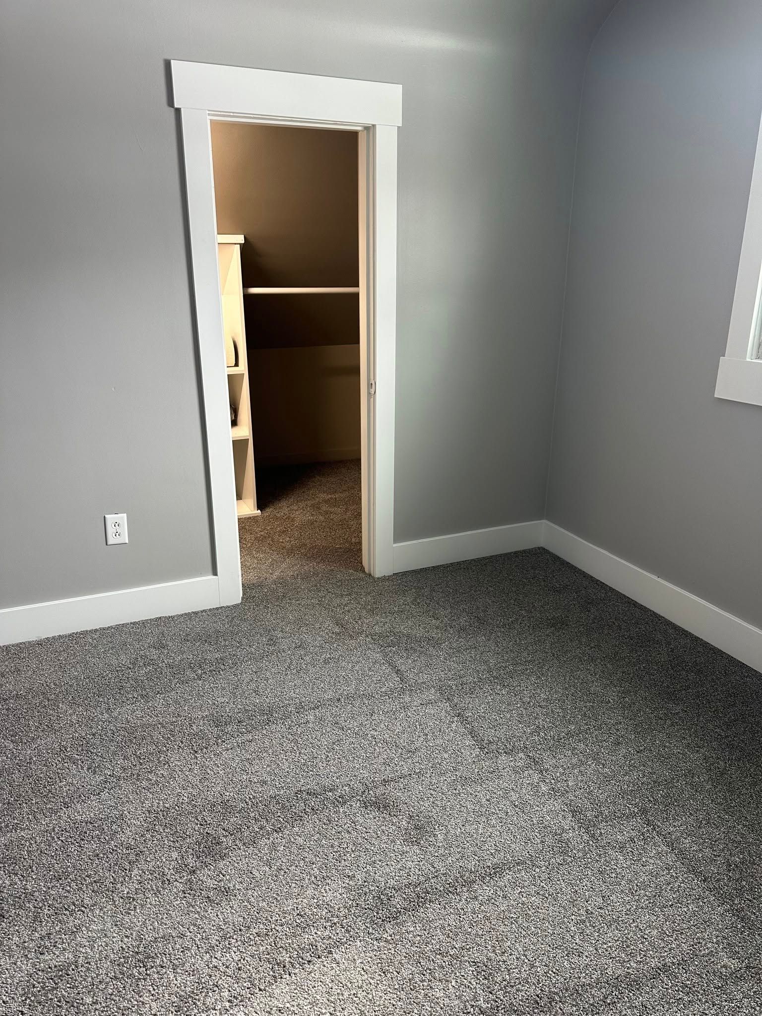 A bedroom with a carpeted floor and a walk in closet.