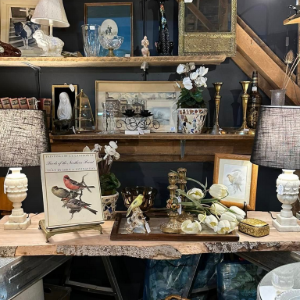 Decorative shelves and table with lamps, framed art, flowers, and assorted home decor items