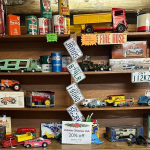 Shelf of colorful toy and collectible cars with signs in a cluttered display.