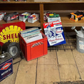Shelves of vintage oil cans and metal tins in a wooden garage display.