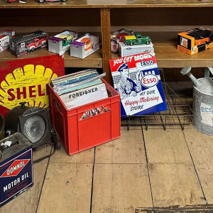 Shelves of vintage oil cans and metal tins in a wooden garage display.