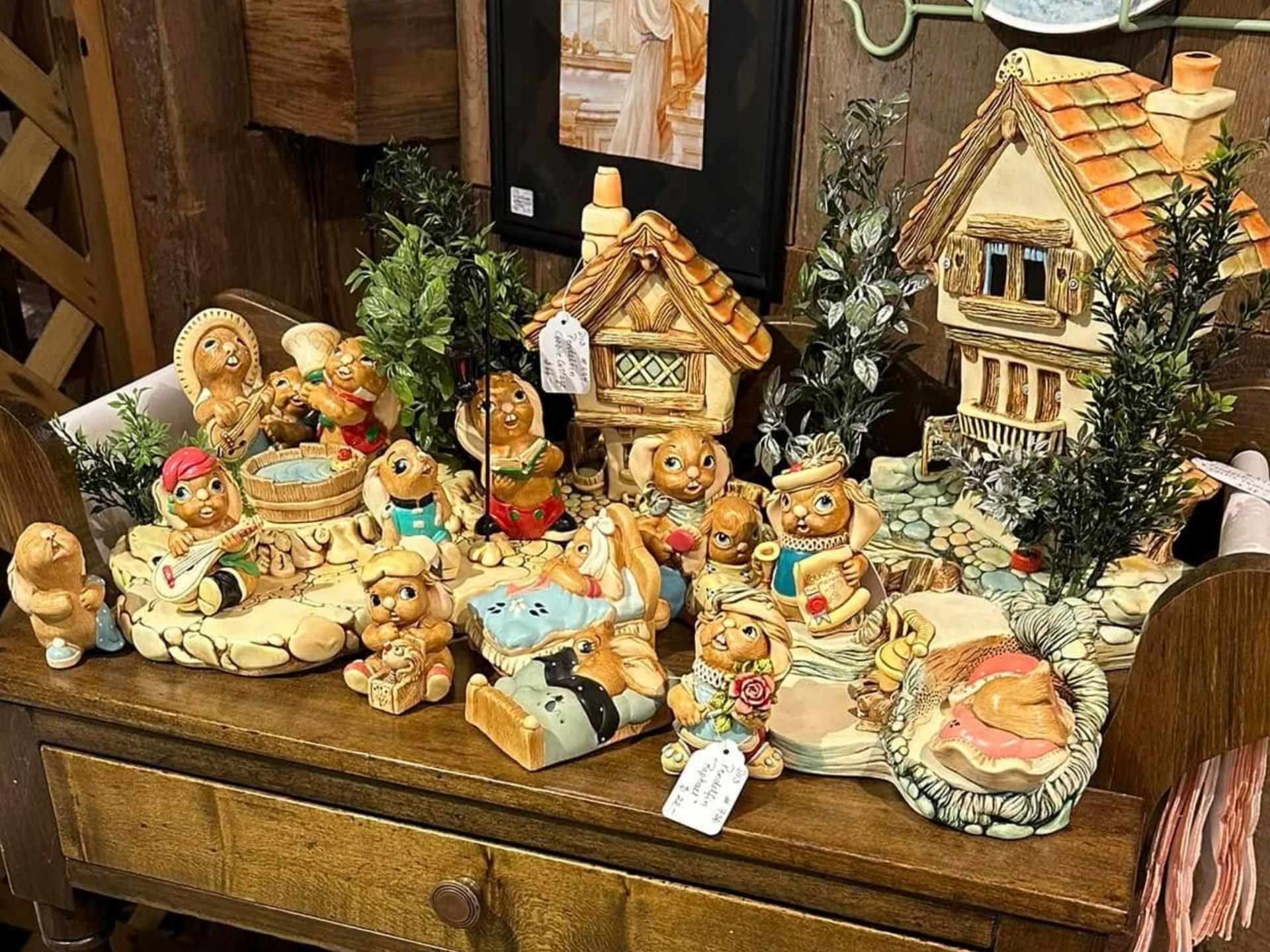 Miniature ceramic village display with teddy bears, tiny houses, and snow-dusted trees on a wooden table