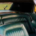 Green leather car seats and rear window with a small horse decal inside a vintage vehicle