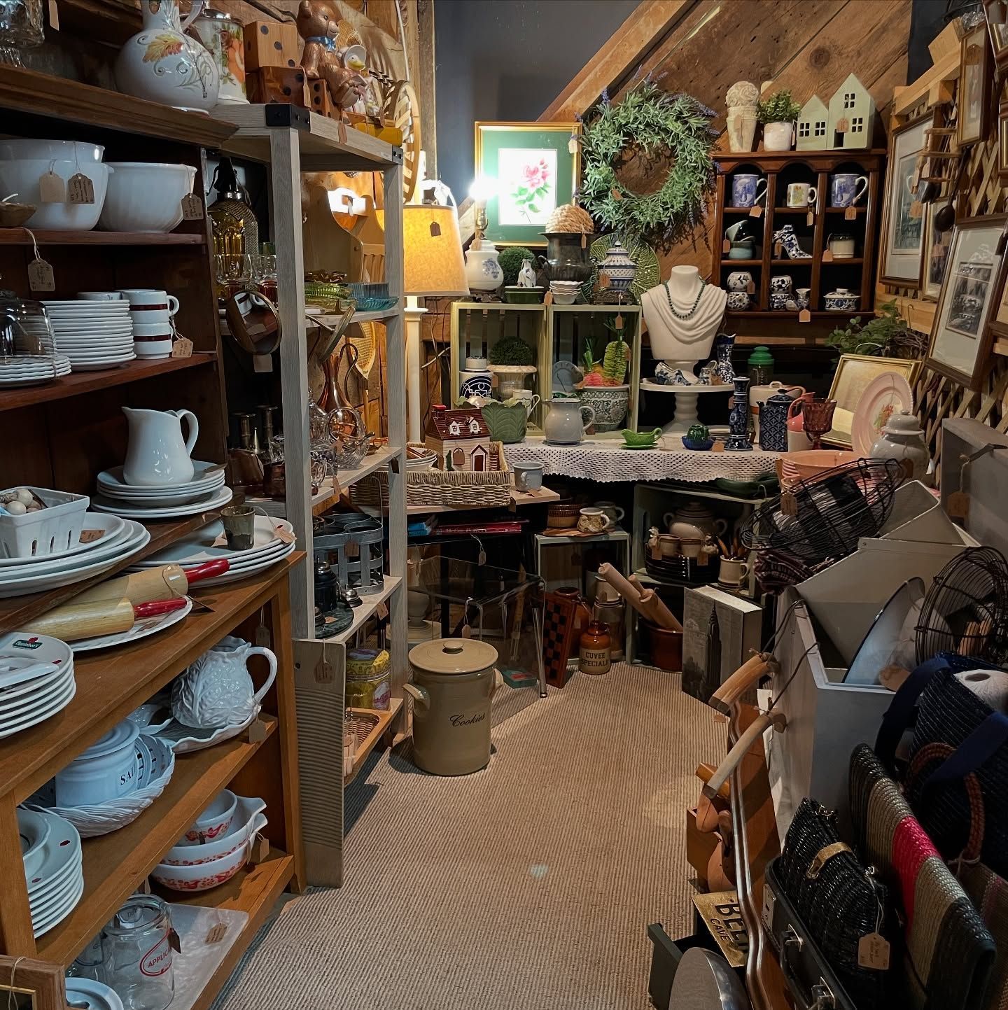 Cozy shop interior with shelves of pottery, teapots, decor, and a small seating area.