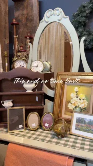 Vintage vanity display with ornate white mirror, framed photos, flowers, and small decorative keepsakes