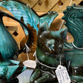 Teal and green glass animal sculptures with price tags on a wooden display shelf
