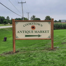 Cookstown Antique Market sign on a grassy roadside, with an arrow pointing right