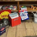 Shelves of vintage oil cans and metal tins in a wooden garage display.