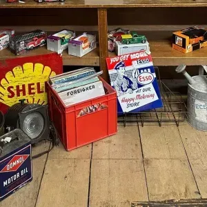 Shelves of vintage oil cans and metal tins in a wooden garage display.