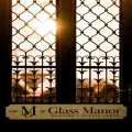Sunlit wrought-iron windows at Glass Manor Wedding and Events Place sign at the bottom