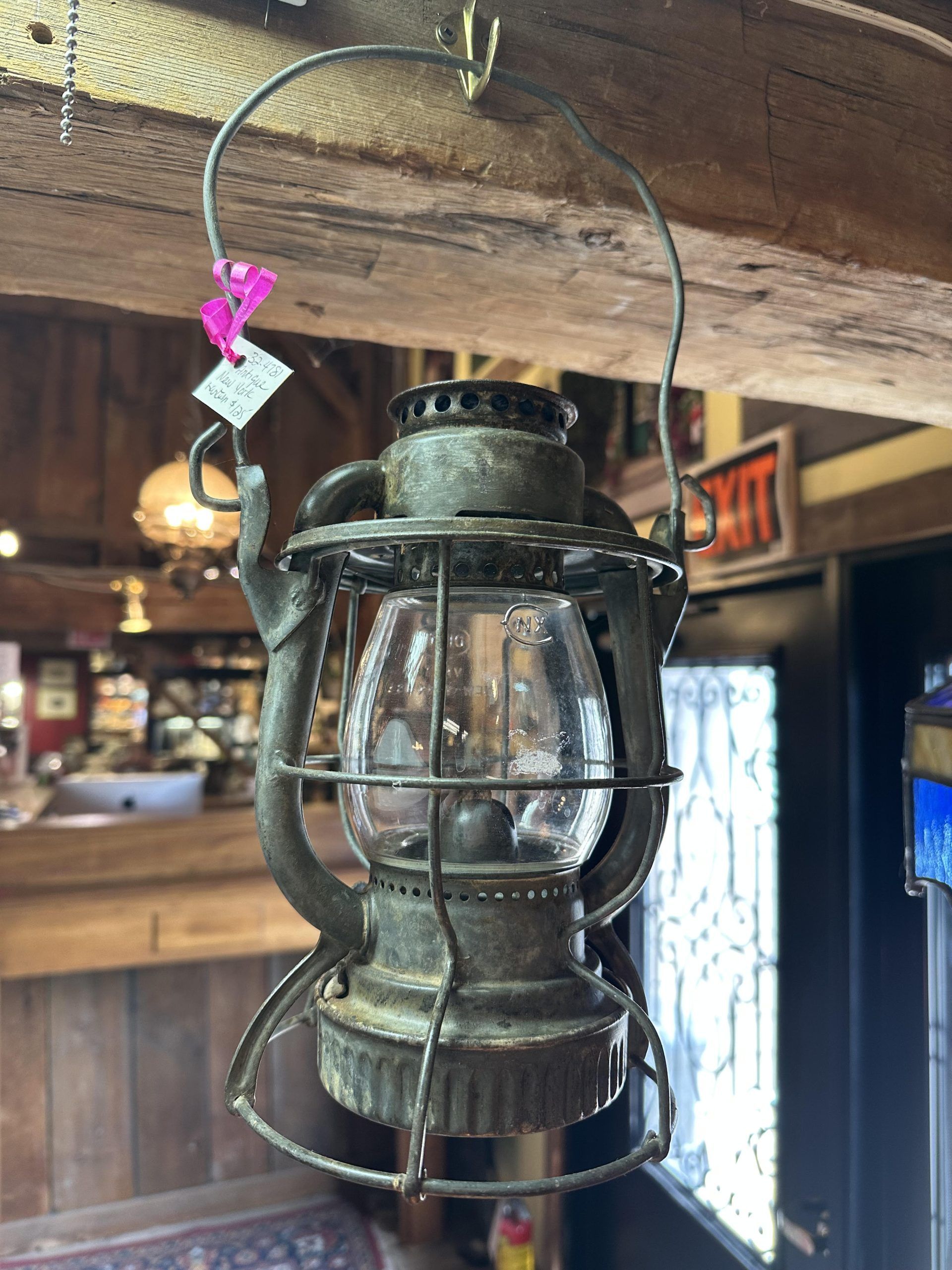 Vintage black lantern hanging inside a rustic wooden shop.