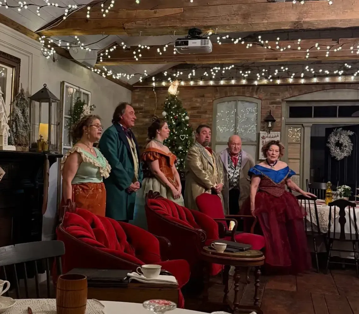 Costumed group standing in a cozy decorated room with string lights and red chairs