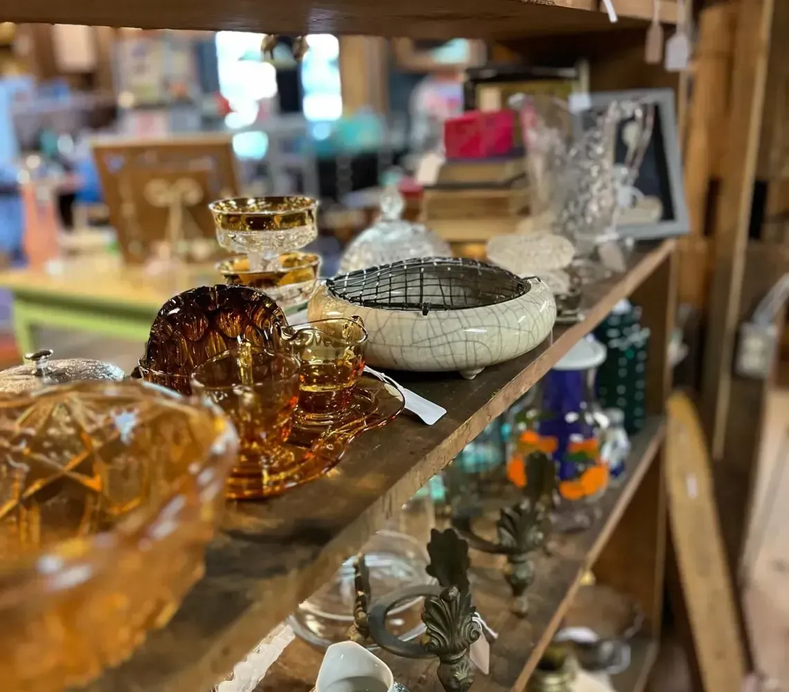 Glass decor and small figurines displayed on wooden shelves in a shop