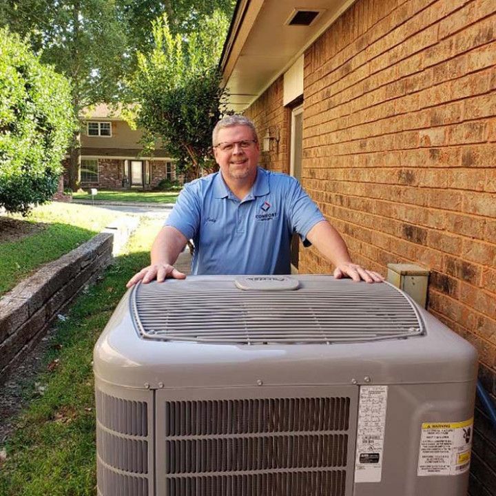 Cody standing next to a large air conditioner outside of a brick building.