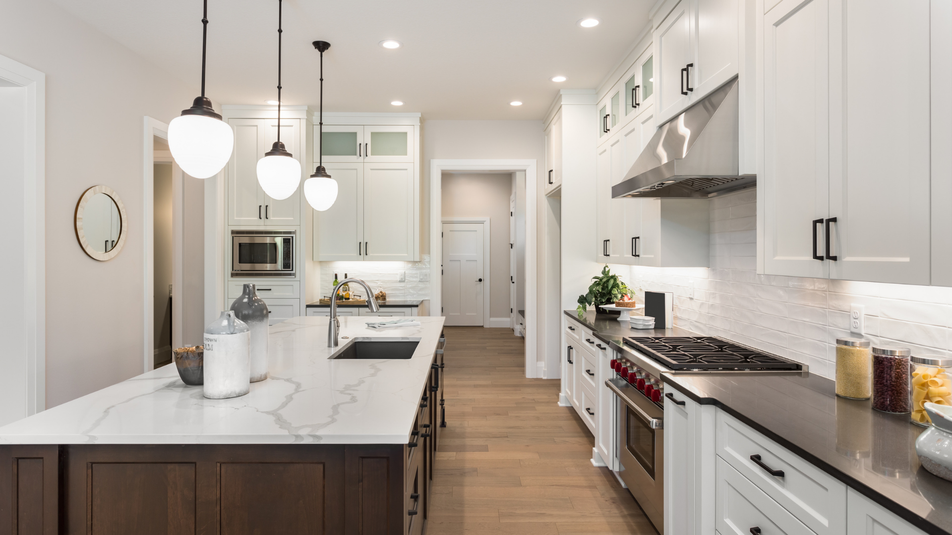 Modern kitchen with white cabinets, marble countertops, and a dark wood island.