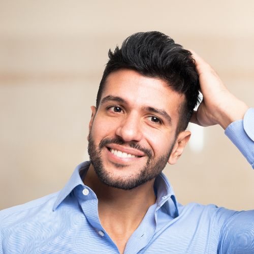 A smiling man running his hand through his hair