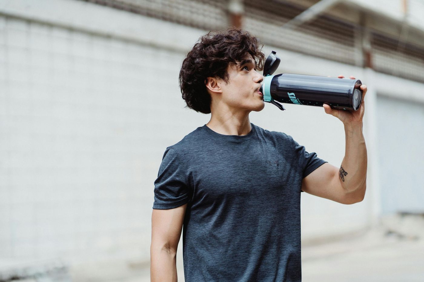 Un hombre tomando agua después de hacer ejercicio
