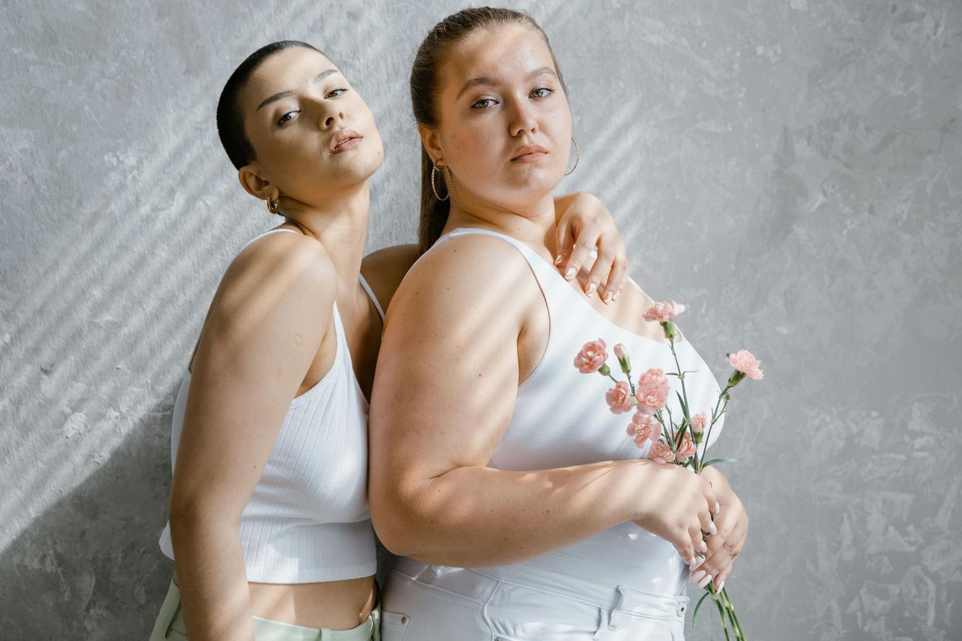 Two women standing together in a bright studio