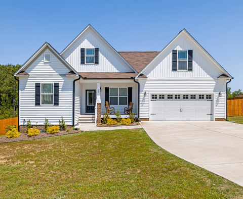 White suburban house with three gables, front porch, and two-car garage under a clear blue sky