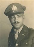 Black-and-white portrait of a man in military uniform and cap, looking at the camera with a slight smile