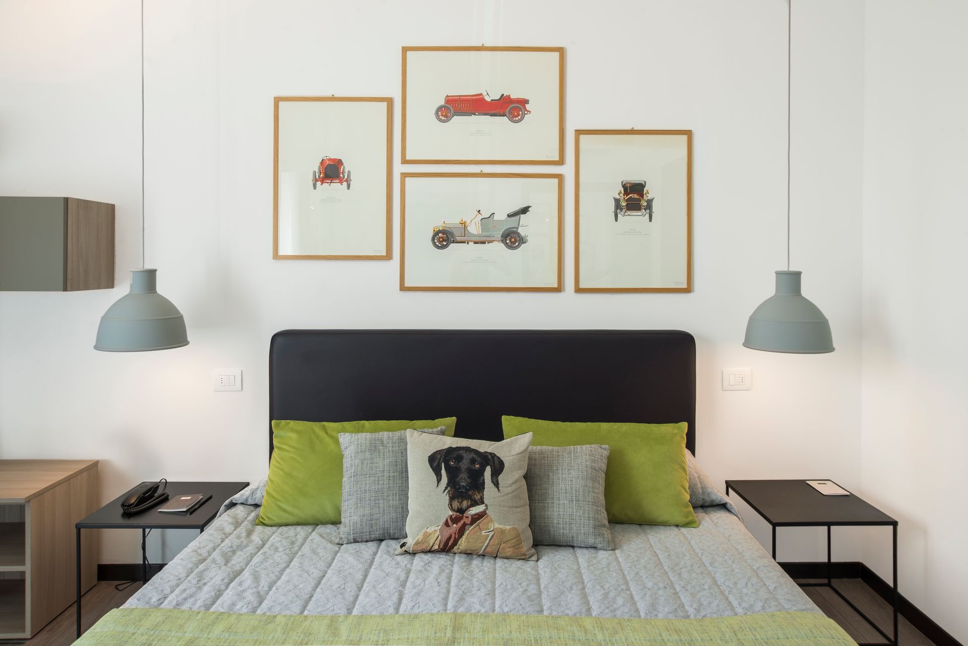 Dormitorio con cama, láminas artísticas, mesitas de noche y lámparas colgantes.