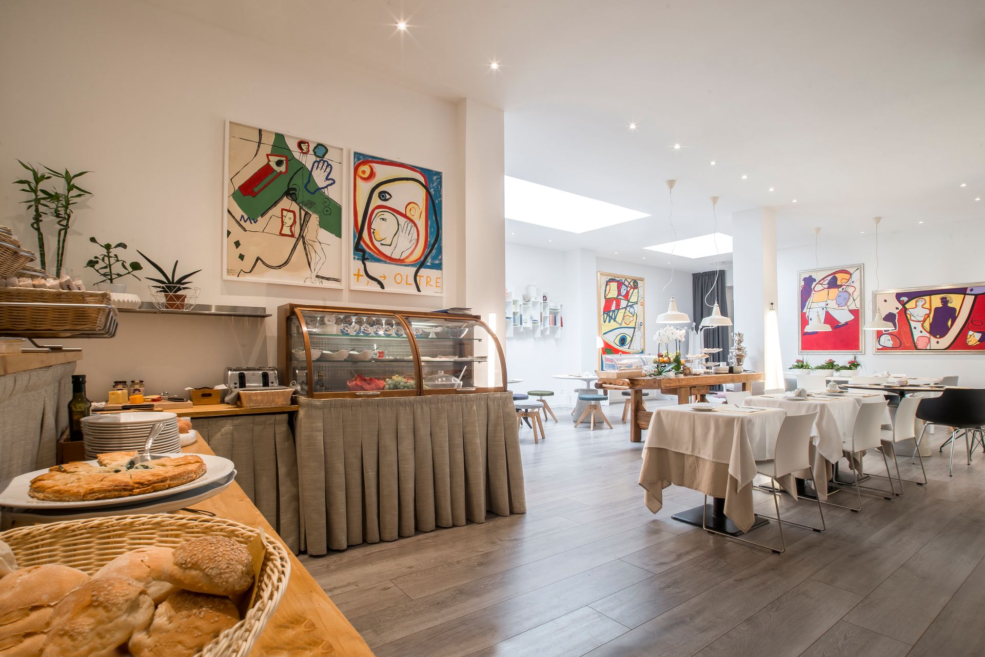 Interior de restaurante con mesa de buffet, obras de arte y mesas de comedor.