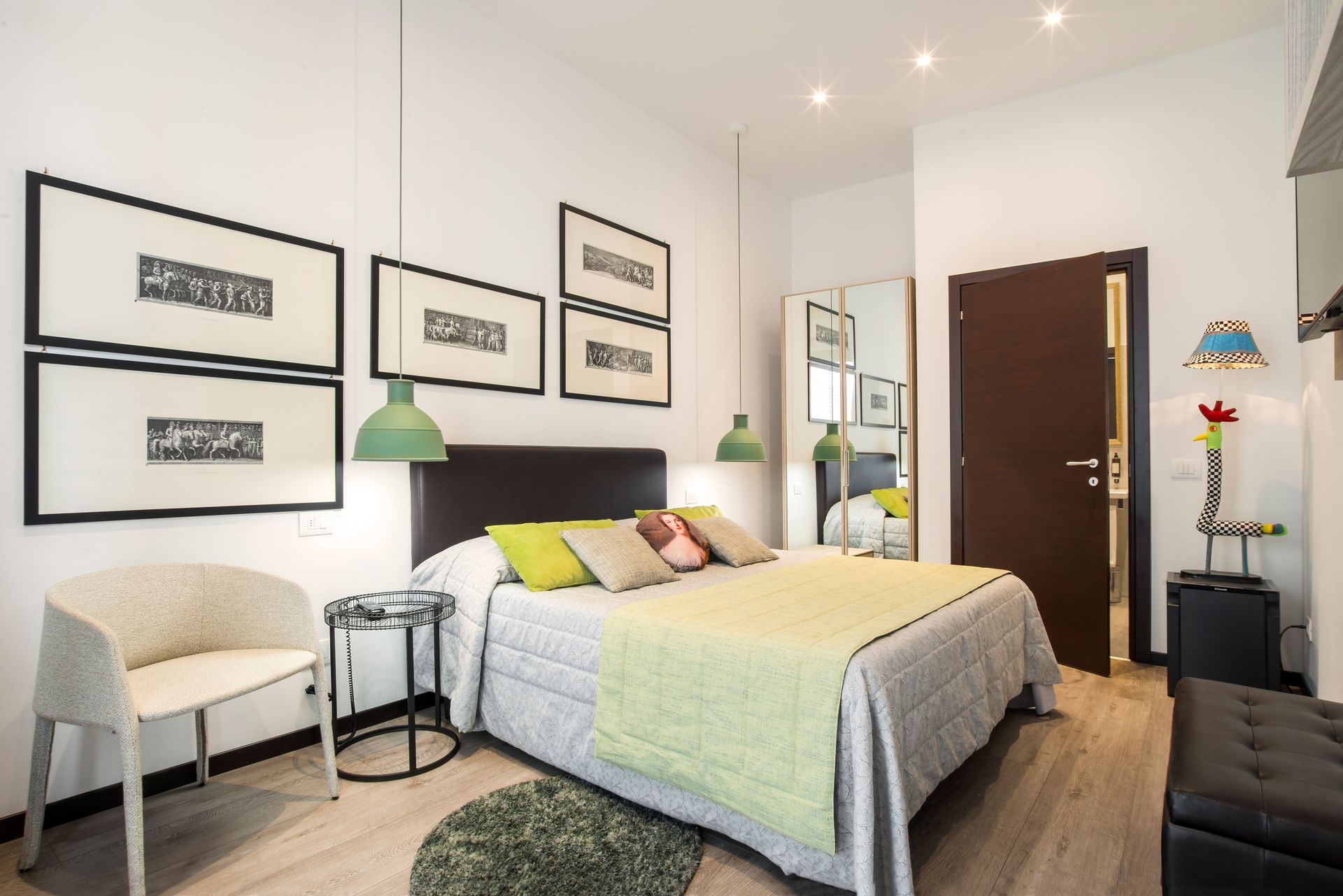 Dormitorio con cama, arte, detalles verdes, silla, espejo y una puerta marrón oscuro.