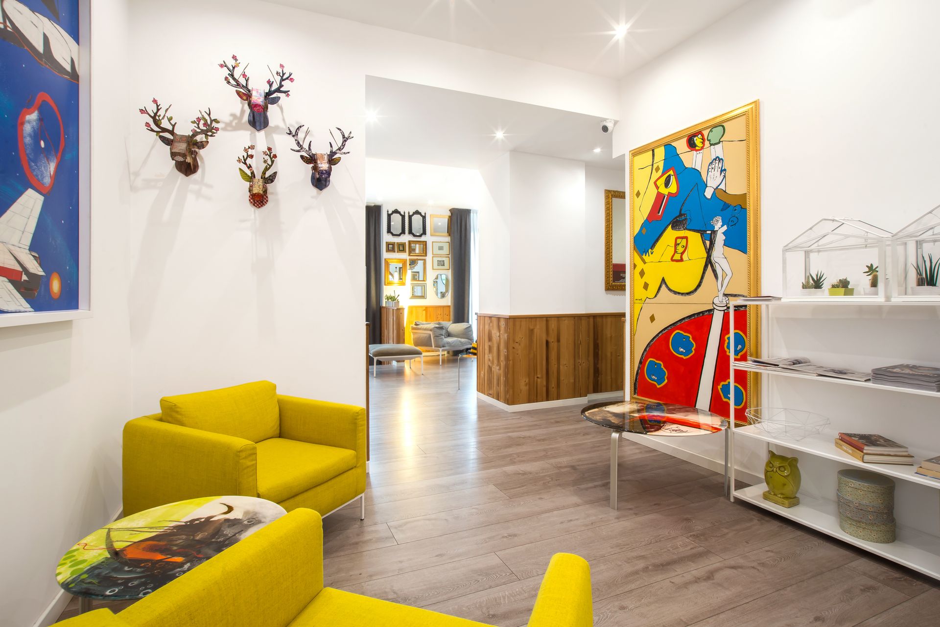 Interior de una galería de arte moderno con asientos amarillos y pinturas coloridas.