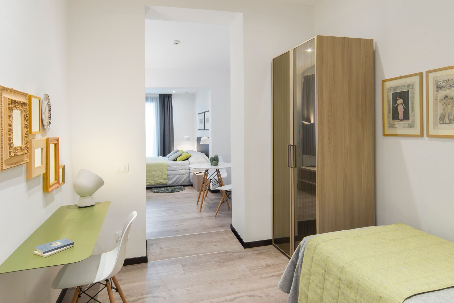 Una habitación de hotel moderna con escritorio, cama y armario. Se ve otra cama en la habitación contigua.