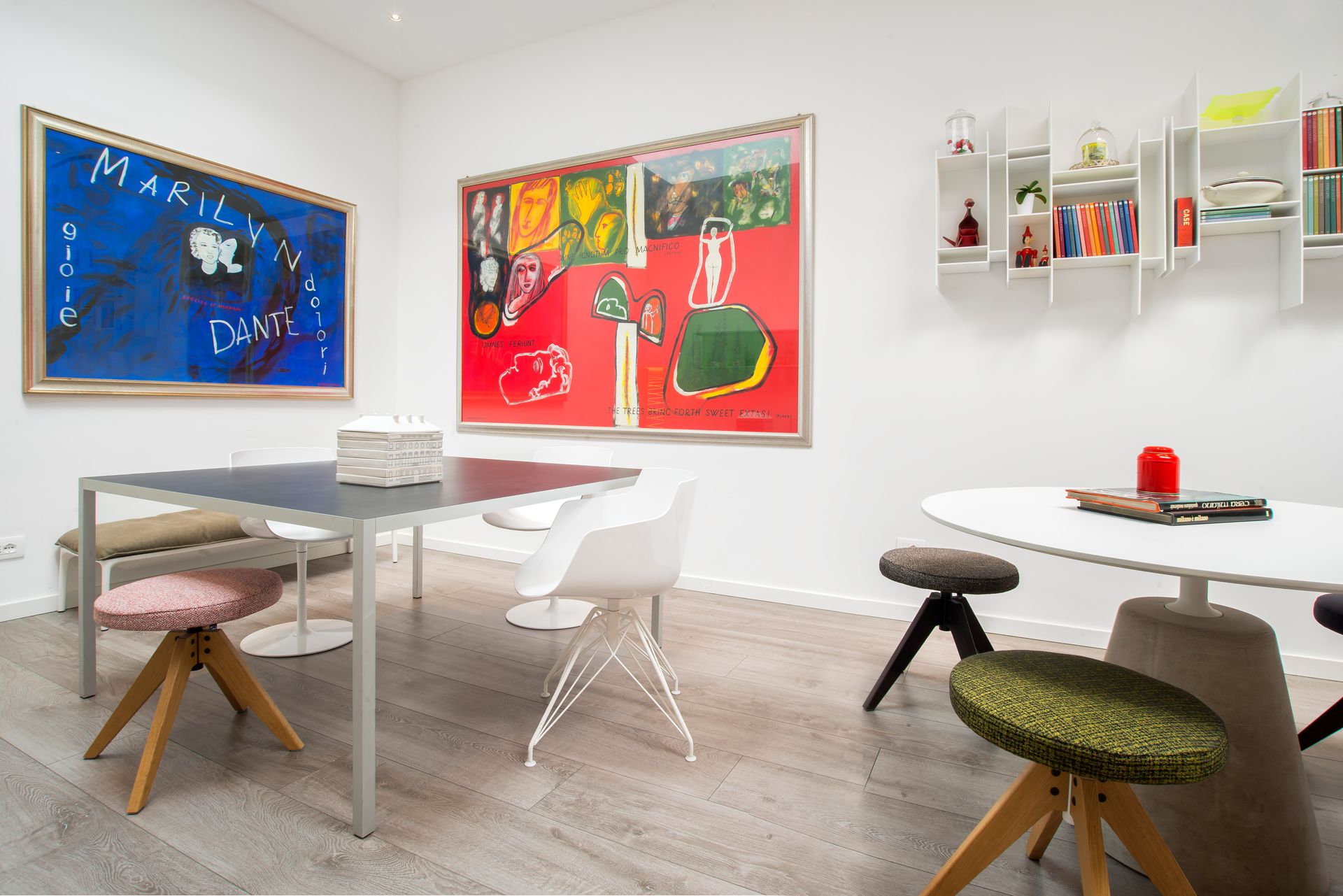 Una galería de arte con muebles modernos. Pinturas azules, rojas y amarillas adornan las paredes blancas.