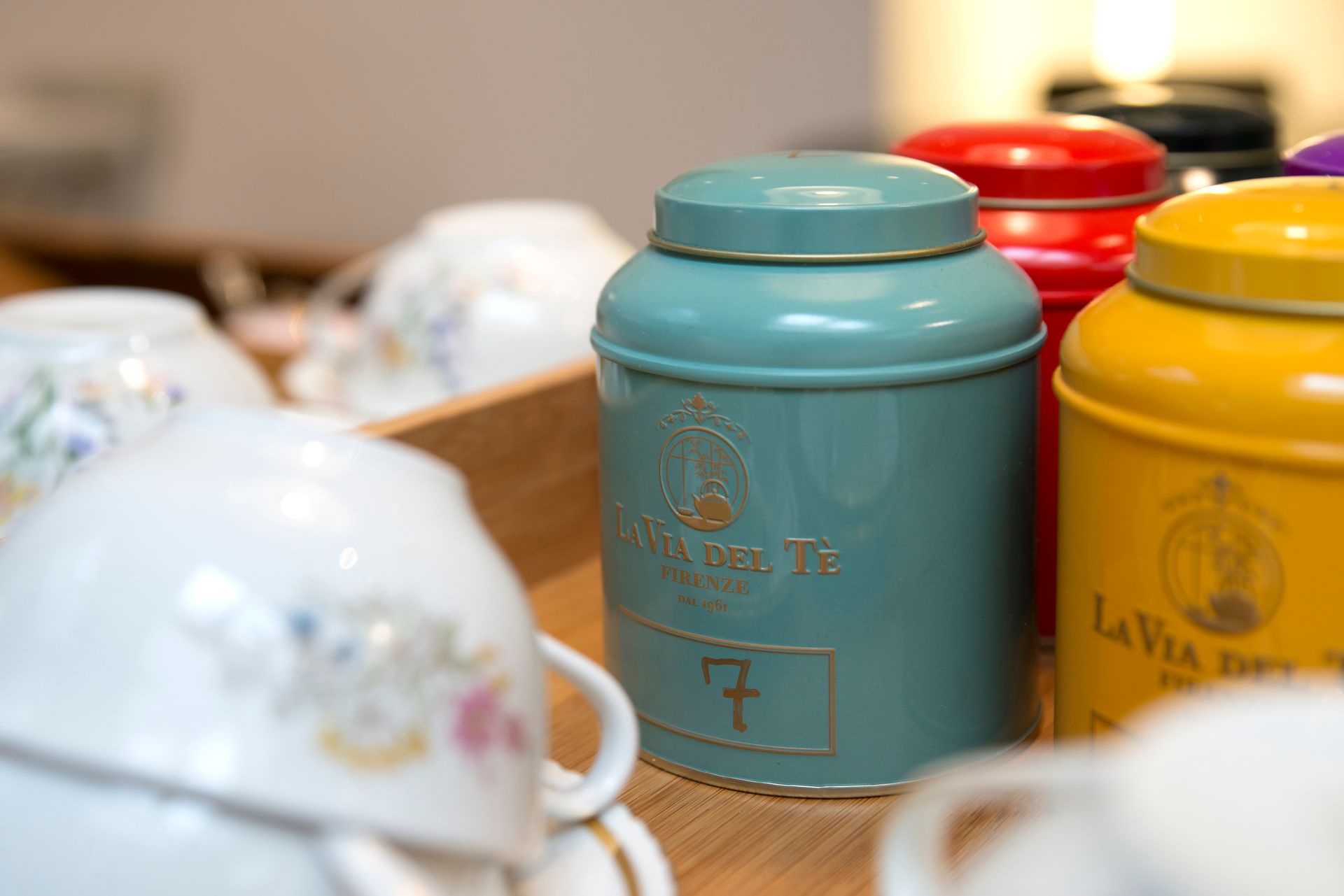 Latas de té de color verde azulado, rojo y amarillo con letras doradas.