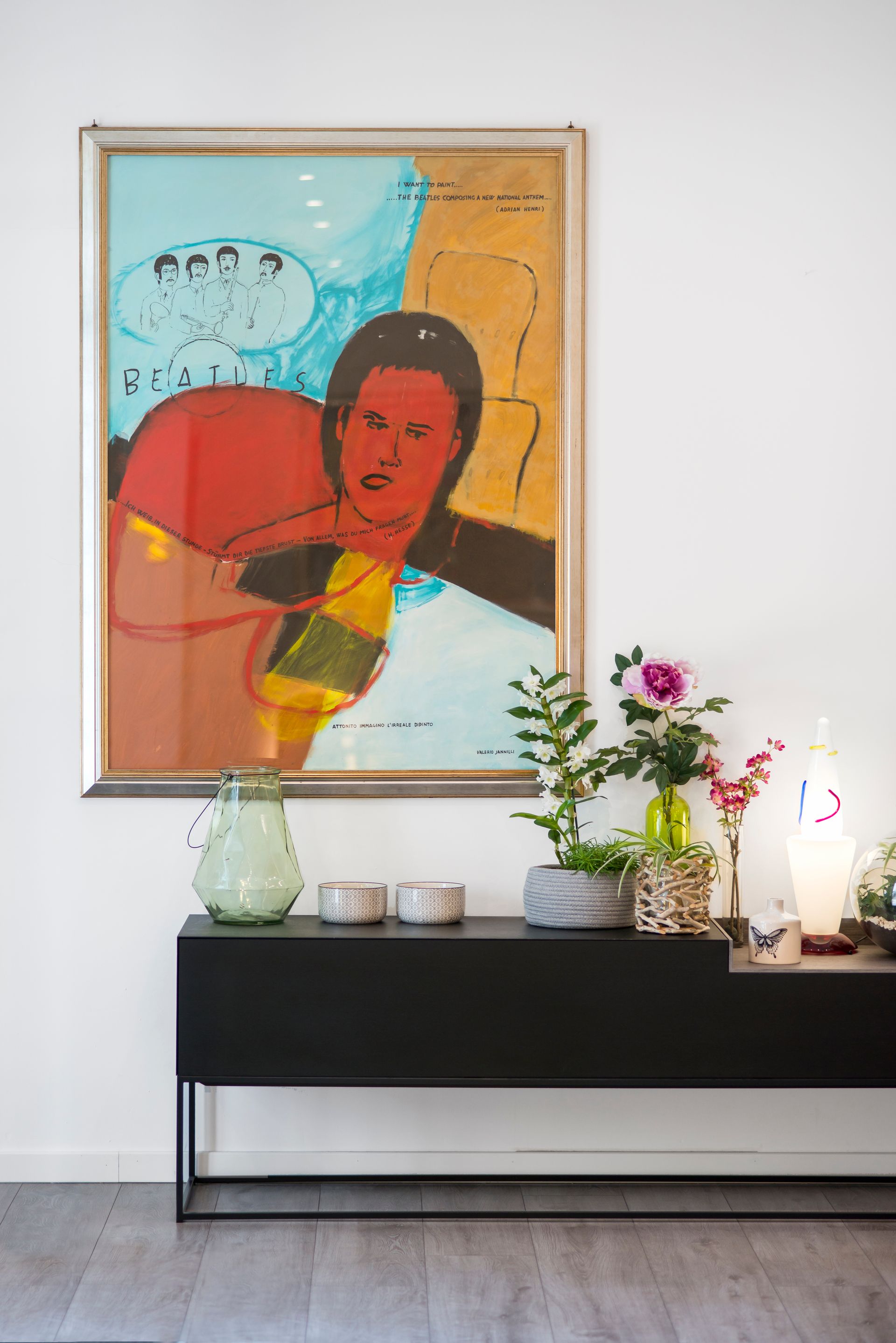 Obra de arte con figura colorida sobre una consola negra con decoración.