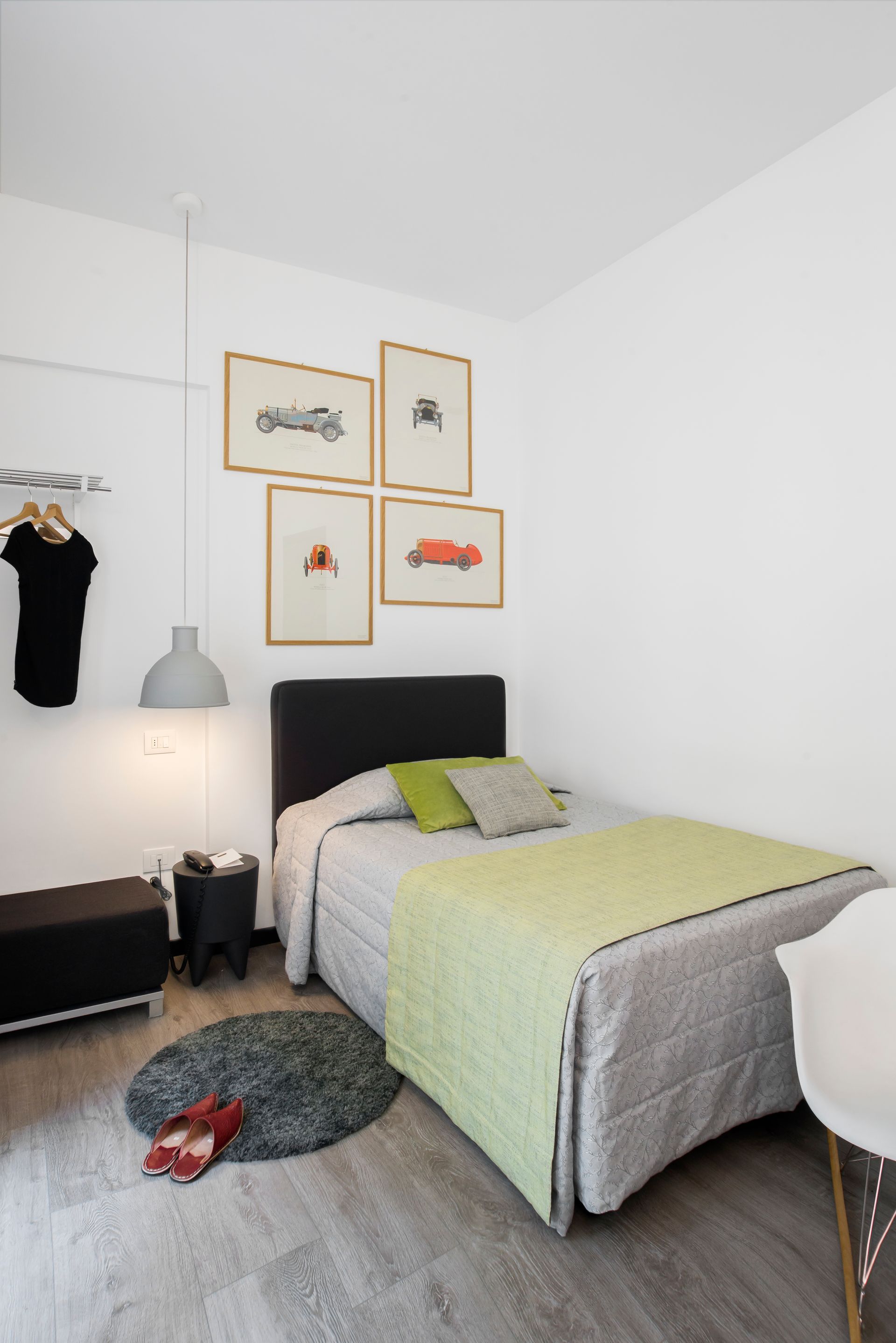 Dormitorio con cama individual, obras de arte y decoración minimalista. Combinación de colores gris, blanco y verde.