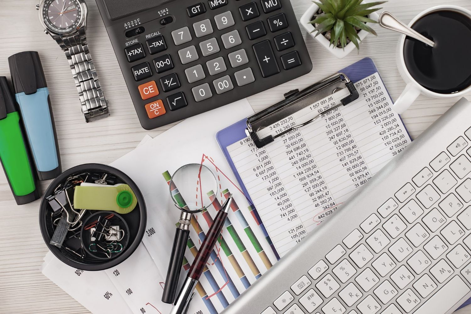 Desk with calculator, paperwork, keyboard, coffee, and office supplies.
