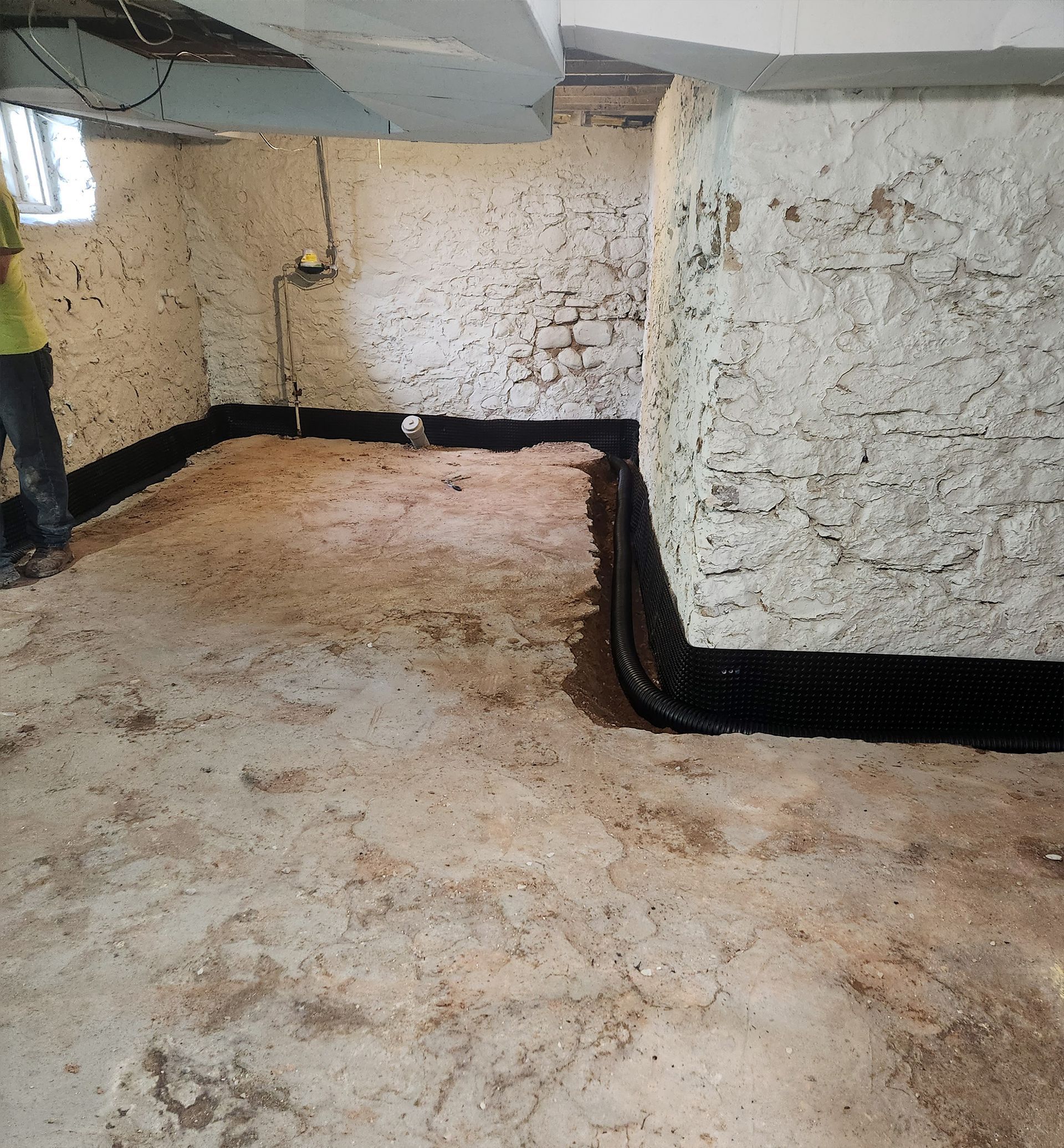 Basement with installed black drainage system along the walls. 